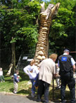Croud of onlookers includeing a community support officer admiring the carving mid way through
