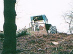 The tractor at the top of a steep banking pulls the heavy tree stem over the virge at the top of the incline