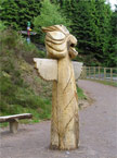 Side view of a massive totem pole which has a head a bit like an eagle, and wings