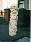 Front view of the three wise monkeys standing on the curb, in the middle of a busy street