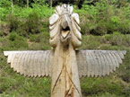 Image of a large pair of wings and a head on top of a Totem pole